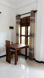 una mesa de madera y una silla en una habitación con ventana en The lookout lodge, en Tangalle