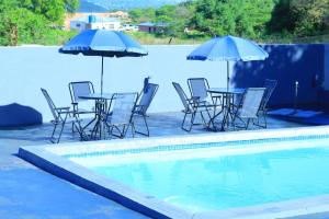 - un groupe de chaises et de tables avec parasols à côté d'une piscine dans l'établissement La Maison Guesthouse, à Thohoyandou