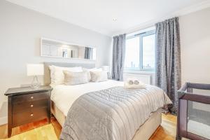 a white bedroom with a bed and a window at Stunning Flat on King's Road, Chelsea with Balcony in London