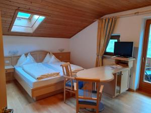 - une chambre avec un lit, un bureau et une table dans l'établissement Appartements Kirchtalhof, à Lana