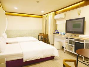 a hotel room with a bed and a flat screen tv at Goodstay Andong Park Hotel in Andong