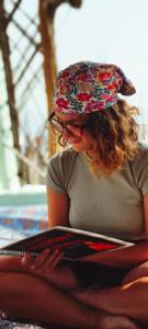 a woman wearing a hat sitting on the ground with a book at Hotel Poonam Pushkar in Pushkar