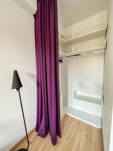 a purple curtain in a room with a closet at Garden Apartment - Herastrau Park 3min Walk in Bucharest