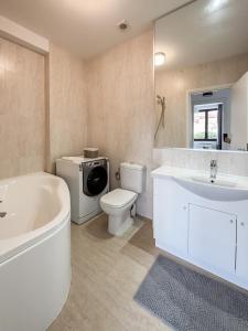 a bathroom with a tub and a toilet and a sink at Garden Apartment - Herastrau Park 3min Walk in Bucharest