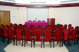 een vergaderzaal met een tafel en rode stoelen bij Hotel KPM Tripenta in Palakkad