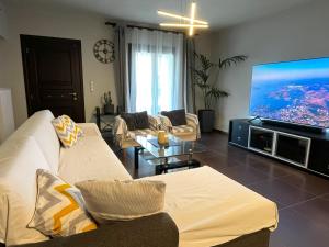 Infinity Horizon Syros Apartment في Lazaréta: غرفة معيشة مع كنب وشاشة تلفزيون كبيرة
