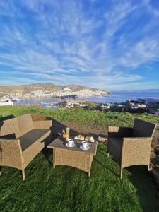 um pátio com duas cadeiras e uma mesa com comida em Infinity Horizon Syros Apartment em Lazaréta