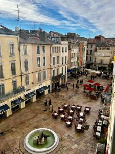 a city with a fountain and tables and buildings at Crocoloft Nimes Centre in Nîmes