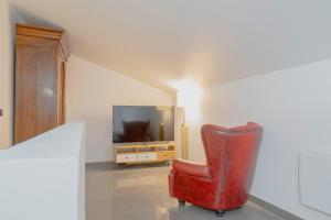 een rode stoel in een woonkamer met een televisie bij Élégant 2 pièces proche de Paris et Disneyland in Neuilly-sur-Marne