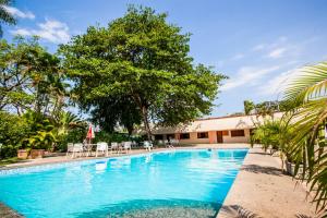 a swimming pool with chairs and a building at Hotel Fazenda Mato Grosso in Cuiabá