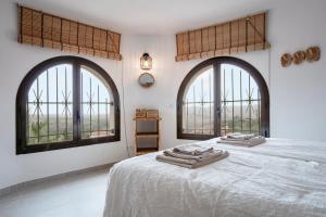 a bedroom with two large windows and a bed with towels on it at Villa Los Primos in Calonge +63 photos