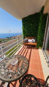 a table and chairs on a balcony with a green wall at Seaview Relax Apartment in Caniço