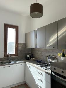 a kitchen with white cabinets and a sink and a stove at Villa Erika Sofja in Porto Palo