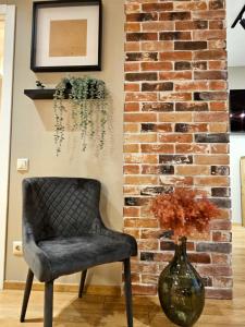 a chair and a vase next to a brick wall at Silversmith's Residence in Old Riga in Rīga