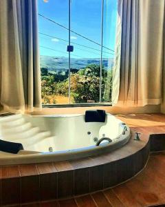 una vasca da bagno in una stanza con una grande finestra di Flat Safira com hidro - Chapada dos Veadeiros a Alto Paraíso de Goiás Altre 20 foto