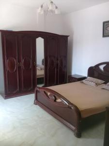 1 dormitorio con 1 cama y armario de madera en maison à louer les grottes Bizerte Tunisie, en Dar el Koudia