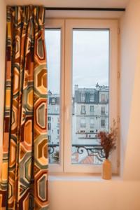 a window with a view of a city at La Maison Montparnasse in Paris