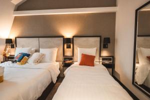 two beds in a hotel room with two mirrors at La Maison Montparnasse in Paris