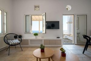 a white living room with a chair and a table at La Chapelle Ouest & Grand suite in Agios Romanos