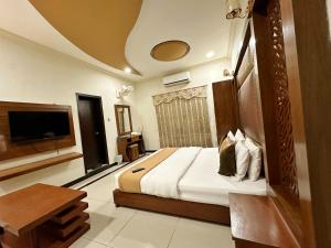um quarto de hotel com uma cama e uma televisão em The Grand Hotel Multan em Multan