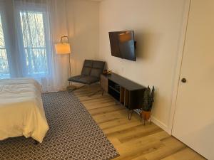a bedroom with a bed and a chair and a flat screen tv at L’espace Mysa - Studio Lugna in Mont-Tremblant