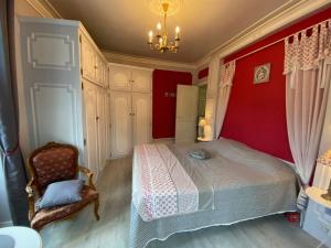 1 dormitorio con paredes rojas, 1 cama y 1 silla en Chambres d'Hôtes La Petite Boynarde, en Rivière-sur-Tarn