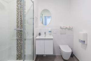 a white bathroom with a toilet and a shower at Vinaura - Appartement élégant avec parking in Reims