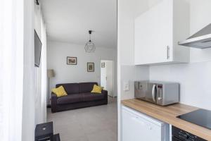 a kitchen and a living room with a couch at Vinaura - Appartement élégant avec parking in Reims