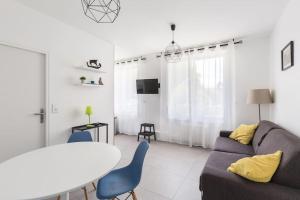 a living room with a couch and a table at Vinaura - Appartement élégant avec parking in Reims