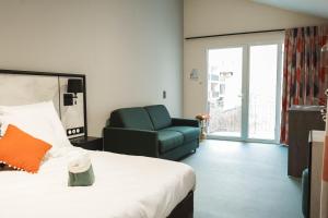 a hotel room with a bed and a green chair at La Maison Montparnasse in Paris