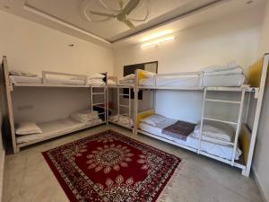Habitación con 3 literas y alfombra. en Hostel Go And Stay Jaisalmer en Jaisalmer
