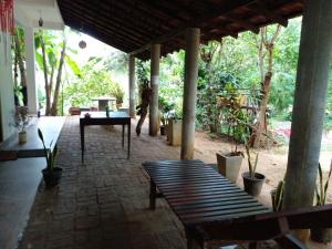 eine Terrasse mit Bänken, einem Tisch und Bäumen in der Unterkunft Ruka Homestay in Tangalle