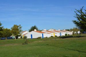 una fila de casas blancas con puertas coloridas en un campo en Charmante Ferme Marine avec piscine commune en Brétignolles-sur-Mer