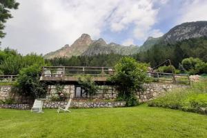 a house in a field with mountains in the background at Maso de Propian in Tesero