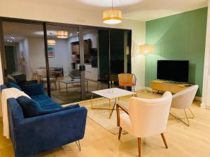 Jolie maison Nantes Zola في نانت: غرفة معيشة مع أريكة زرقاء وتلفزيون