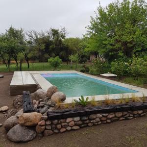 uma piscina num quintal com uma parede de pedra em Morada de encuentro em Capilla del Monte