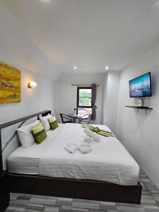 een slaapkamer met een groot wit bed en een tv aan de muur bij Samui Green Hotel in Chaweng Beach