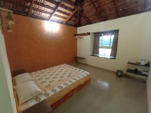 um quarto com uma cama e uma janela em Sarvoday Eco Homestay, Sawantwadi em Sawantwadi