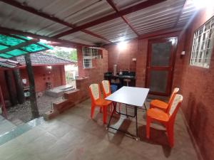 une salle à manger avec une table et des chaises blanches dans l'établissement Sarvoday Eco Homestay, Sawantwadi, à Sawantwadi