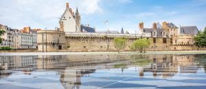 un viejo castillo con un reflejo en un cuerpo de agua en Jolie maison Nantes Zola en Nantes