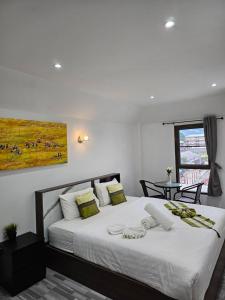 a bedroom with a large white bed and a table at Samui Green Hotel in Chaweng