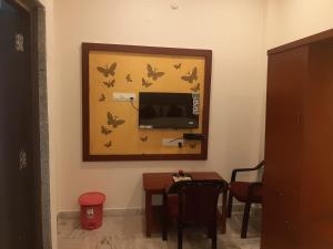 Habitación con TV y mesa con mariposas en la pared. en Hotel Sri Sai Residency en Khammam