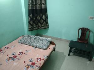 - une petite chambre avec un lit et une chaise dans l'établissement New Milan Palace, DEOGHAR, à Deoghar