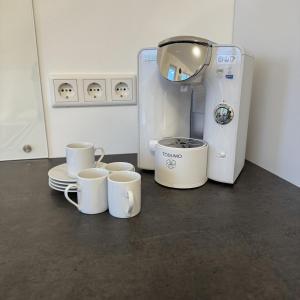 eine Kaffeemaschine mit Tassen und Tellern auf der Theke in der Unterkunft Ferienwohnung Auf Der Höll 