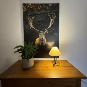 eine Lampe auf einem Holztisch mit einem Bild eines Hirsches in der Unterkunft Ferienwohnung Auf Der Höll 