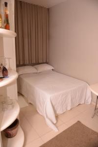 a small bedroom with a white bed with a window at Otimo Flat c WI-FI no centro de Santa Rosa in Santa Rosa