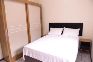 a bedroom with a bed with white sheets and pillows at Incrivel apto completo e confortavel Santa Rosa RS in Santa Rosa