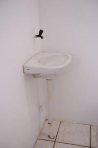 lavabo blanco en un baño blanco con grifo en Apto c Wifi e otima localizacao em Santa Rosa RS en Santa Rosa