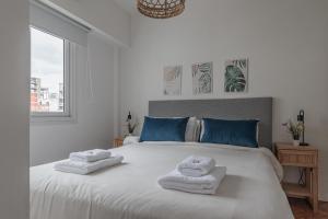 a bedroom with a white bed with towels on it at Fliphaus Melo 2900 - 1 Bd Alto Palermo in Buenos Aires