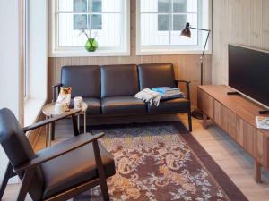 a living room with a leather couch and a television at Holiday home Averøy VII in Karvåg